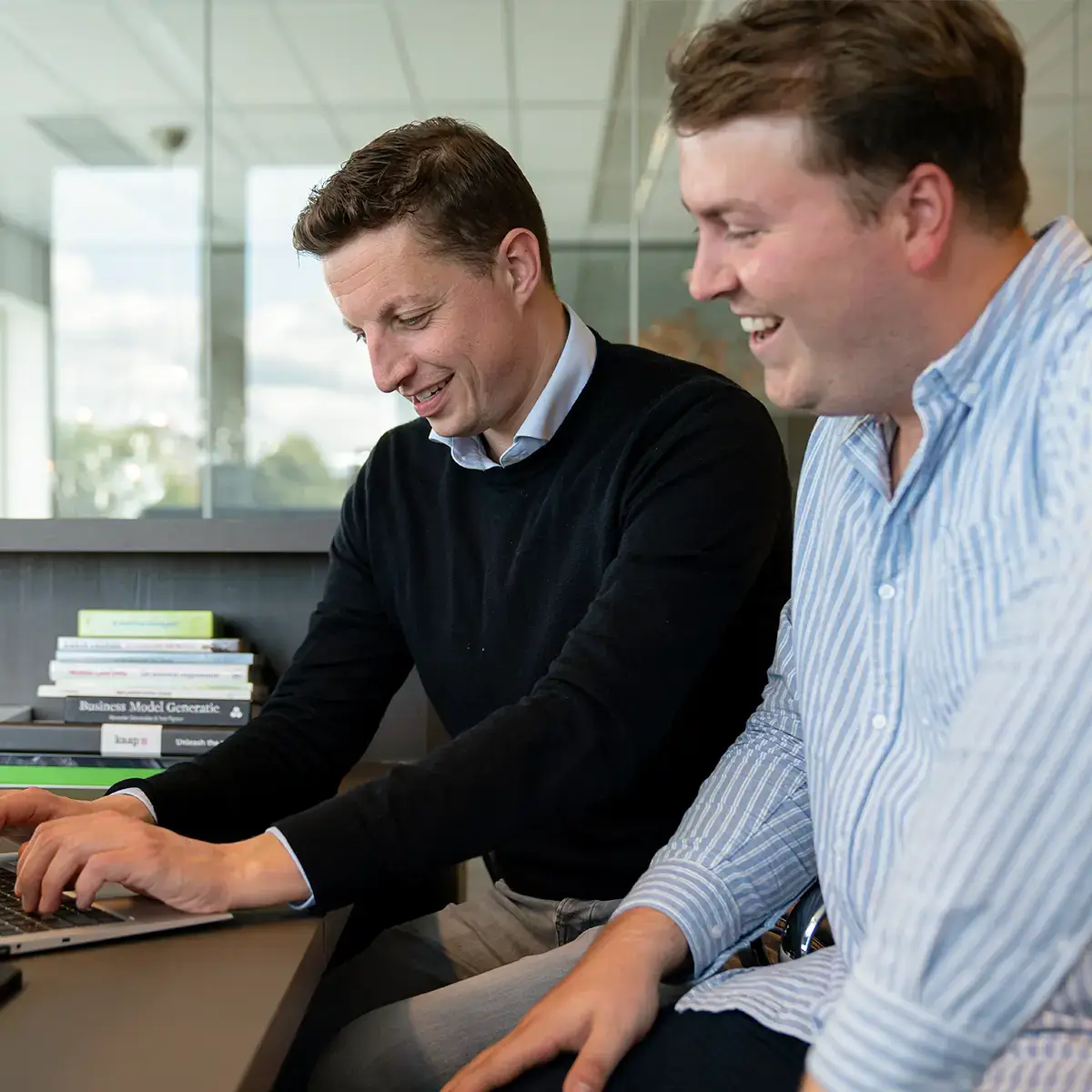 Twee collega's in gesprek in een informele setting, illustratie van de voordelen van het kiezen voor payroll services ten opzichte van zelf verlonen.